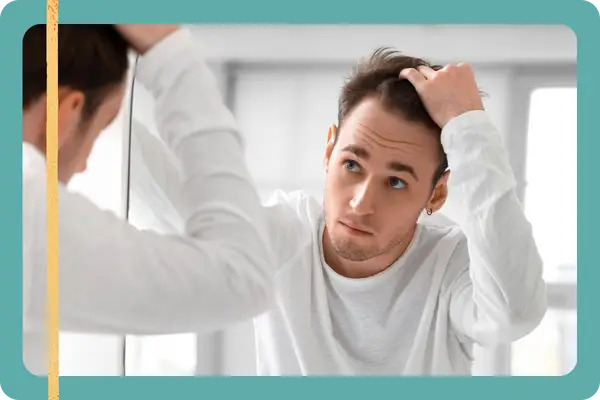 man looking at his hair in the mirrow